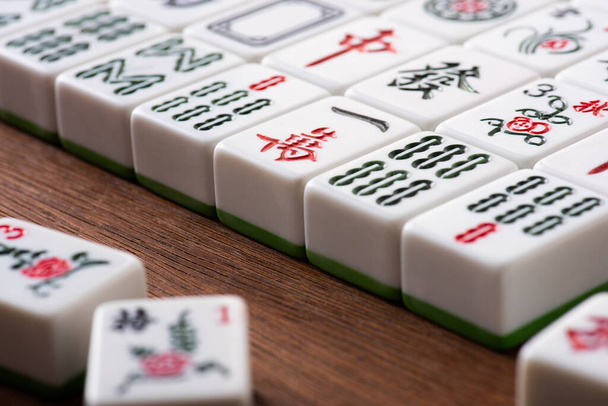 KYIV, UKRAINE - JANUARY 30, 2019: selective focus of white mahjong game tiles with signs and characters on wooden table - Foto, Bild
