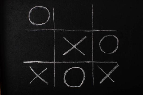 top view of tic tac toe game on blackboard with chalk grid, naughts and crosses  - Foto, afbeelding
