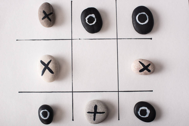 top view of tic tac toe game with stones marked with naughts and crosses on white paper - Photo, Image