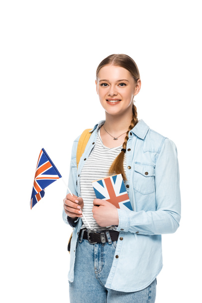 χαμογελαστή όμορφη μαθήτρια με σακίδιο κρατώντας βιβλίο και βρετανική σημαία που απομονώνονται σε λευκό - Φωτογραφία, εικόνα