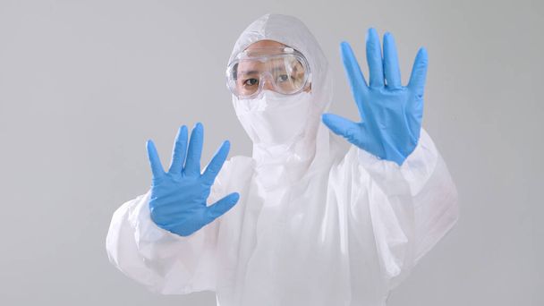 Retrato médico asiático en traje PPE mostrar un gesto no o detener
 - Foto, Imagen