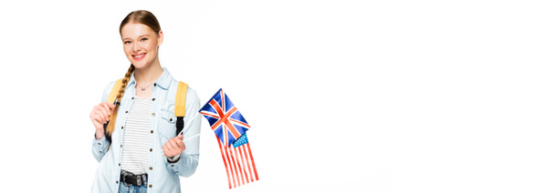 白いパノラマのショットに隔離されたアメリカとイギリスの旗を持っているブレイドとバックパックを持つ笑顔の女の子 - 写真・画像