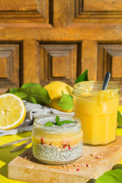 Vegetarian healthy eating and dieting food concept. Vegan chia pudding with fresh homemade granola and lemon curd for breakfast. Trendy sunny, vivid, harsh and hard light, shadows and background  - Photo, Image