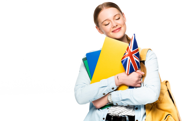menina sorridente com mochila e olhos fechados segurando copybooks e bandeira uk isolado no branco
 - Foto, Imagem