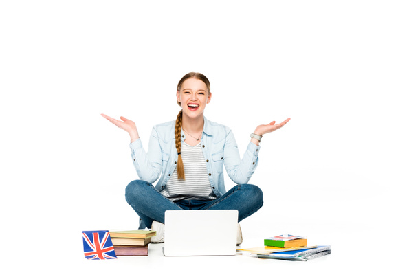 chica feliz sentado en el suelo con el ordenador portátil, libros y copybooks, bandera del Reino Unido y gesto aislado en blanco
 - Foto, Imagen
