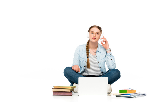menina sentada no chão em fones de ouvido perto de laptop, livros e cadernos isolados em branco
 - Foto, Imagem