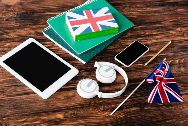 gadgets near books and copybooks and uk flags on wooden table - Foto, Bild