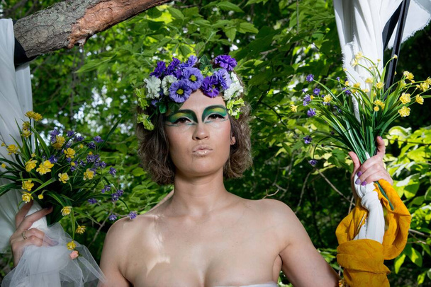 beautiful bride in a wreath of flowers posing in forest - Fotó, kép