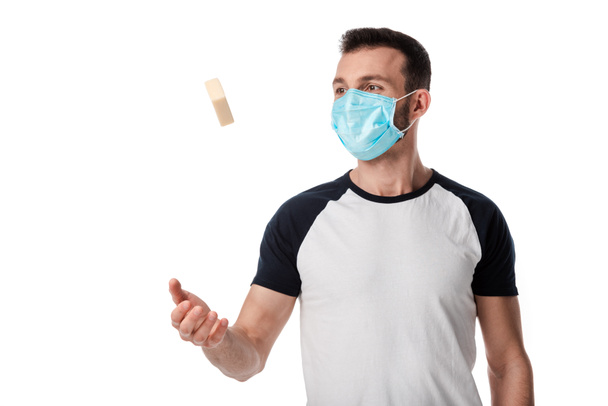 man in medical mask throwing in air soap bar isolated on white  - Фото, изображение
