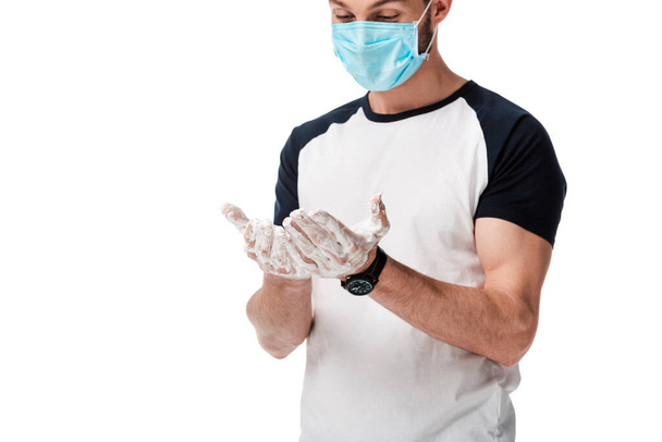 мужчина в медицинской маске смотрит на мыльные руки, изолированные на белом
  - Фото, изображение