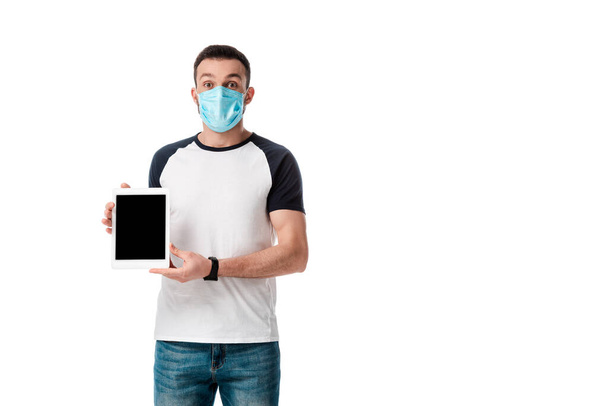 mężczyzna w masce medycznej trzymając cyfrowy tablet z pustym ekranem izolowanym na białym  - Zdjęcie, obraz