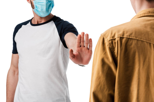 обрезанный вид человека в медицинской маске, показывающий стоп-жест рядом с парнем, изолированным на белом
  - Фото, изображение