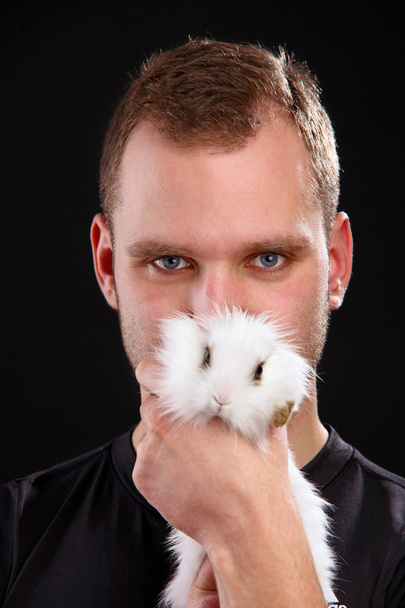 Young man and domestic rabbit on black background - Zdjęcie, obraz