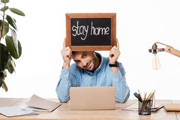 feliz freelancer sosteniendo pizarra con letras de la estancia en casa aislado en blanco
  - Foto, Imagen