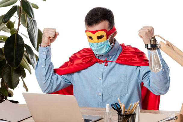 фрилансер в медицинской маске и в плаще супергероя с ноутбуком, изолированным на белом
  - Фото, изображение