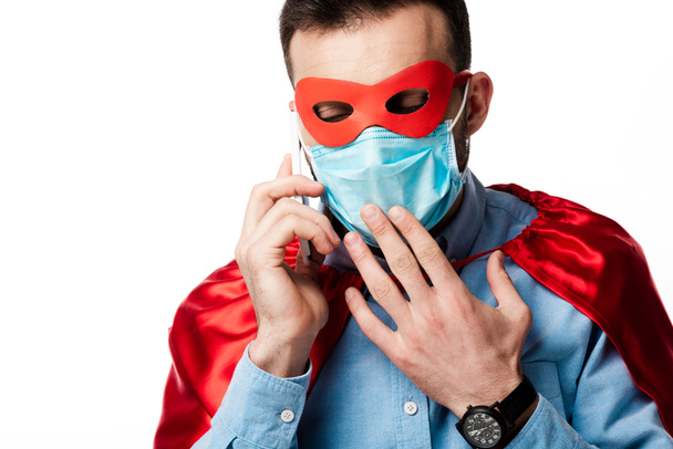 man in superhero costume and medical mask talking on smartphone isolated on white   - Foto, Imagem