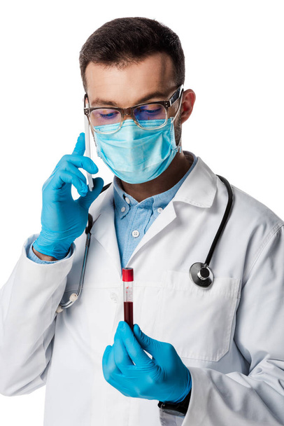 medico in maschera medica e occhiali che parla sullo smartphone mentre tiene in mano la provetta con campione di sangue isolato su bianco
  - Foto, immagini