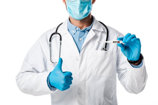 vista ritagliata del medico in maschera medica e mantello bianco con termometro digitale e mostrando pollice in alto isolato su bianco
  - Foto, immagini