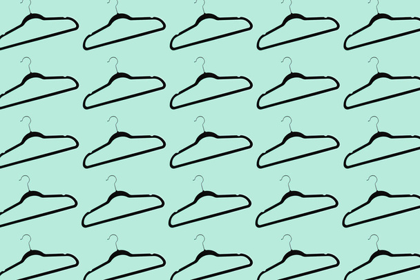 Pattern of black hangers isolated on background of aqua menthe color. - Photo, Image