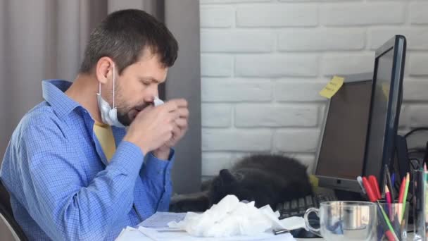 Ένας άρρωστος άντρας φυσάει τη μύτη του σε ένα μαντήλι, δουλεύοντας εξ αποστάσεως σε καραντίνα. - Πλάνα, βίντεο