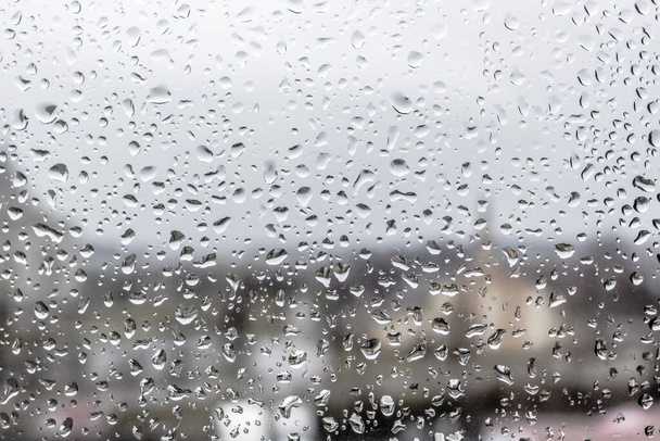 Ανοιξιάτικη βροχή Είθε η καταιγίδα. Σταγόνες βροχής στο ποτήρι. Η υφή των σταγόνων. Υγρό παράθυρο. Χαλαρή μέρα. Άσχημος καιρός. Κατακλυσμική βροχή. Άποψη του κόσμου από το παράθυρο. - Φωτογραφία, εικόνα