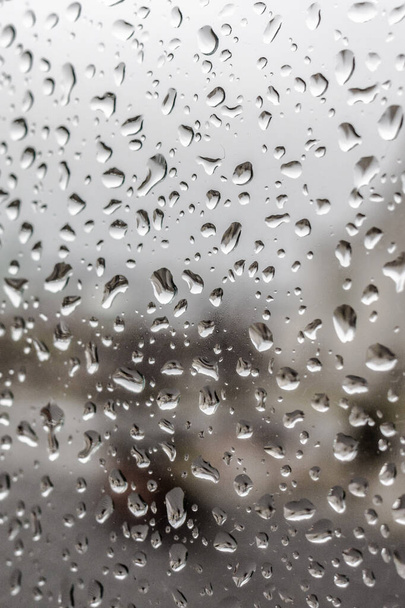 春の雨。5月の雷雨。ガラスに雨が降る。滴の質感。濡れた窓。寒い日だ。悪天候だ。豪雨。窓からの世界観. - 写真・画像