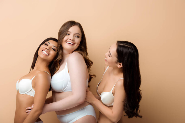 happy plus size multicultural girls in bras isolated on beige  - Zdjęcie, obraz