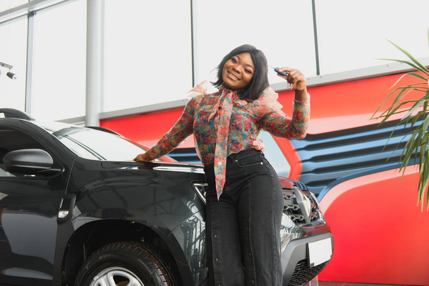 Woman buying the car. Lady in a car salon. Elegant black girl. woman in car salon - Zdjęcie, obraz