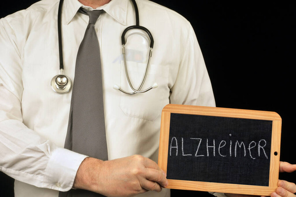 Doctor sosteniendo una pizarra escolar con Alzheimer escrito en ella
  - Foto, Imagen