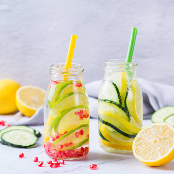 Gezondheidszorg, fitness, gezonde voeding dieet concept. Verse koele citroenkomkommer rozemarijn granaatappel geïnfundeerd water, detox drank, limonade in een glazen pot voor de lente zomerdagen.  - Foto, afbeelding