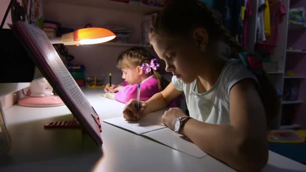 Deux filles font leurs devoirs tard le soir, à la lumière d'une lampe de table
 - Séquence, vidéo
