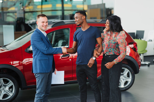 happy woman receiving a new car from her husband at dealership - Photo, Image