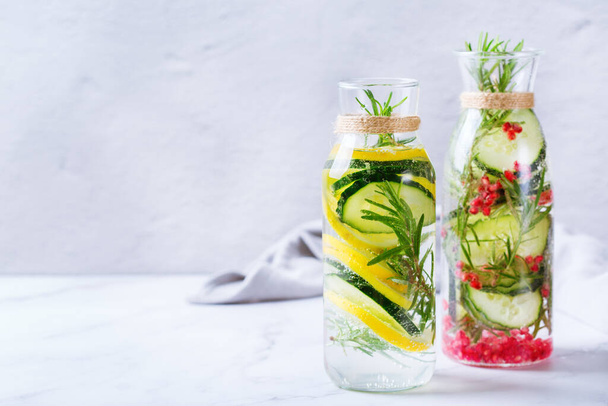 Health care, fitness, healthy nutrition diet concept. Fresh cool lemon cucumber rosemary pomegranate infused water, detox drink, lemonade in a glass jar for spring summer days.  Copy space background - Photo, Image