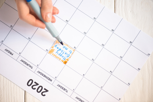 Vista cortada de mulher apontando com caneta marcador no feliz aniversário para mim lettering no calendário de tarefas com inscrição 2020 em fundo de madeira
 - Foto, Imagem