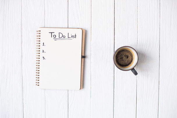 Vista superior do notebook com para fazer lista de letras e xícara de café em fundo de madeira
 - Foto, Imagem