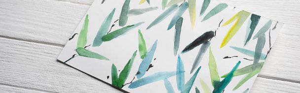 Top view of paper with Japanese painting with multicolored leaves on wooden background, panoramic shot - Fotó, kép