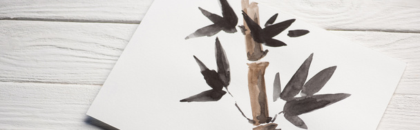 Vista superior de papel com pintura japonesa com bambu e folhas em fundo de madeira, tiro panorâmico
 - Foto, Imagem