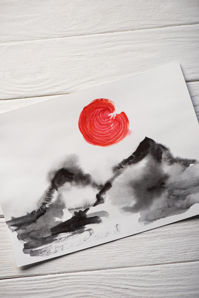 Top view of paper with Japanese painting with hills and red sun on wooden background - Photo, Image