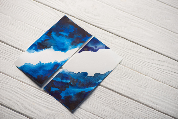 Visão de alto ângulo de papel com pintura japonesa com aquarela azul brilhante no fundo de madeira
 - Foto, Imagem
