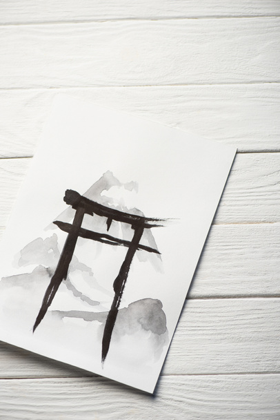 Top view of paper with japanese painting with black hieroglyph on wooden background - Фото, изображение