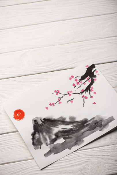 Υψηλή γωνία άποψη του χαρτιού με γιαπωνέζικη ζωγραφική με ήλιο, Sakura κλαδιά και λόφος σε ξύλινο φόντο - Φωτογραφία, εικόνα