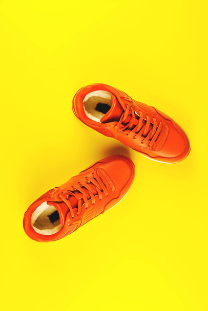 Orange sneakers on yellow background. Concept of sport and healthy lifestyle. - 写真・画像