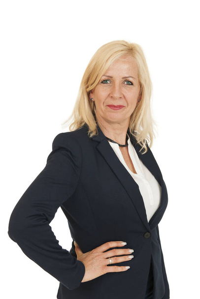 Lateral torso view of a blonde long-haired middle-aged woman in a black blazer and hand on hip smiling friendly at the camera against white background. - Фото, изображение