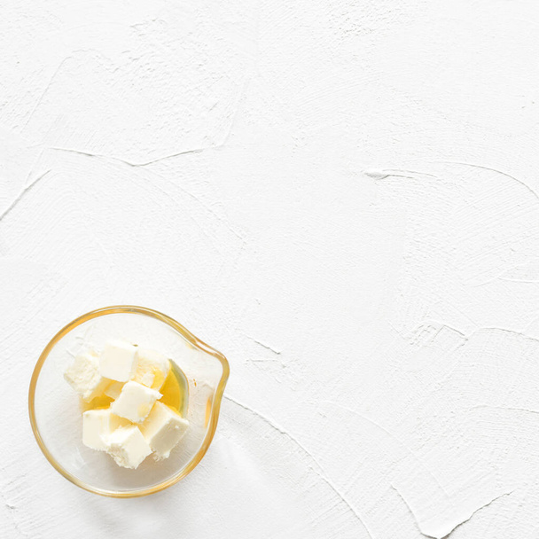 Slices of melted butter in bowl on  white background. Overhead view - Photo, image