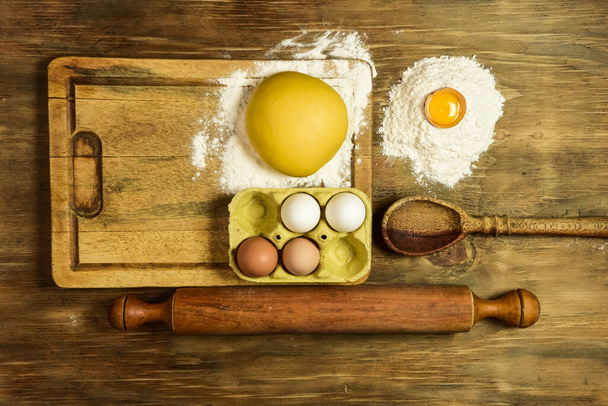 Vaječné těsto na nudle se ingrediencemi na stole. - Fotografie, Obrázek
