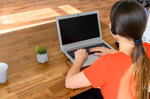 Young woman works from home using headset, laptop - Photo, image