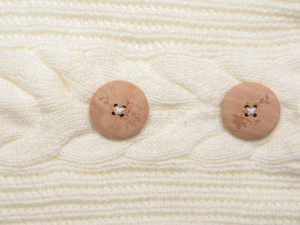 un bouton en bois est cousu à un vêtement tricoté en laine
 - Photo, image