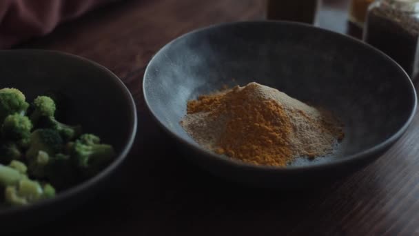 On the kitchen table are bowls with a mixture of spices and broccoli for preparing healthy foods. Close-up - Footage, Video