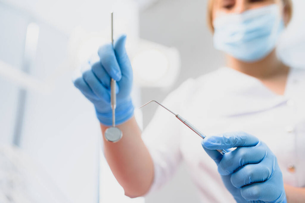 Portrait of a dentist holding dental instruments in his hands in the clinic close-up - Foto, Imagen
