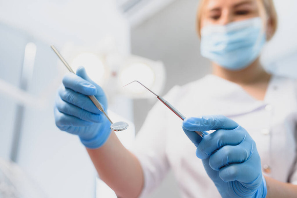 Portret dentysty trzymającego przyrządy dentystyczne w dłoniach w klinice zbliżenie - Zdjęcie, obraz